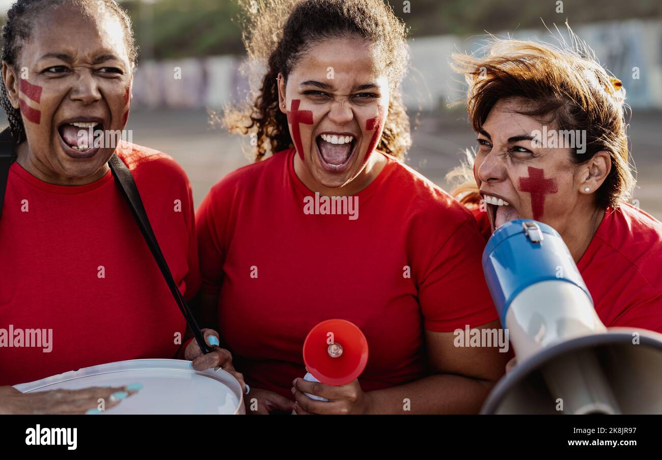 Les fans de football féminin s'exclatent tout en regardant un match de football au stade - les femmes au visage peint et au mégaphone encouragent leur équipe Banque D'Images