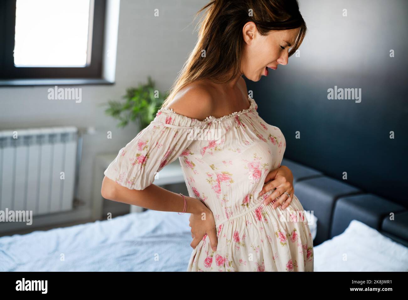 Femme enceinte s'attendant à un bébé avec des douleurs, des nausées, des maux de tête et des maux de dos Banque D'Images