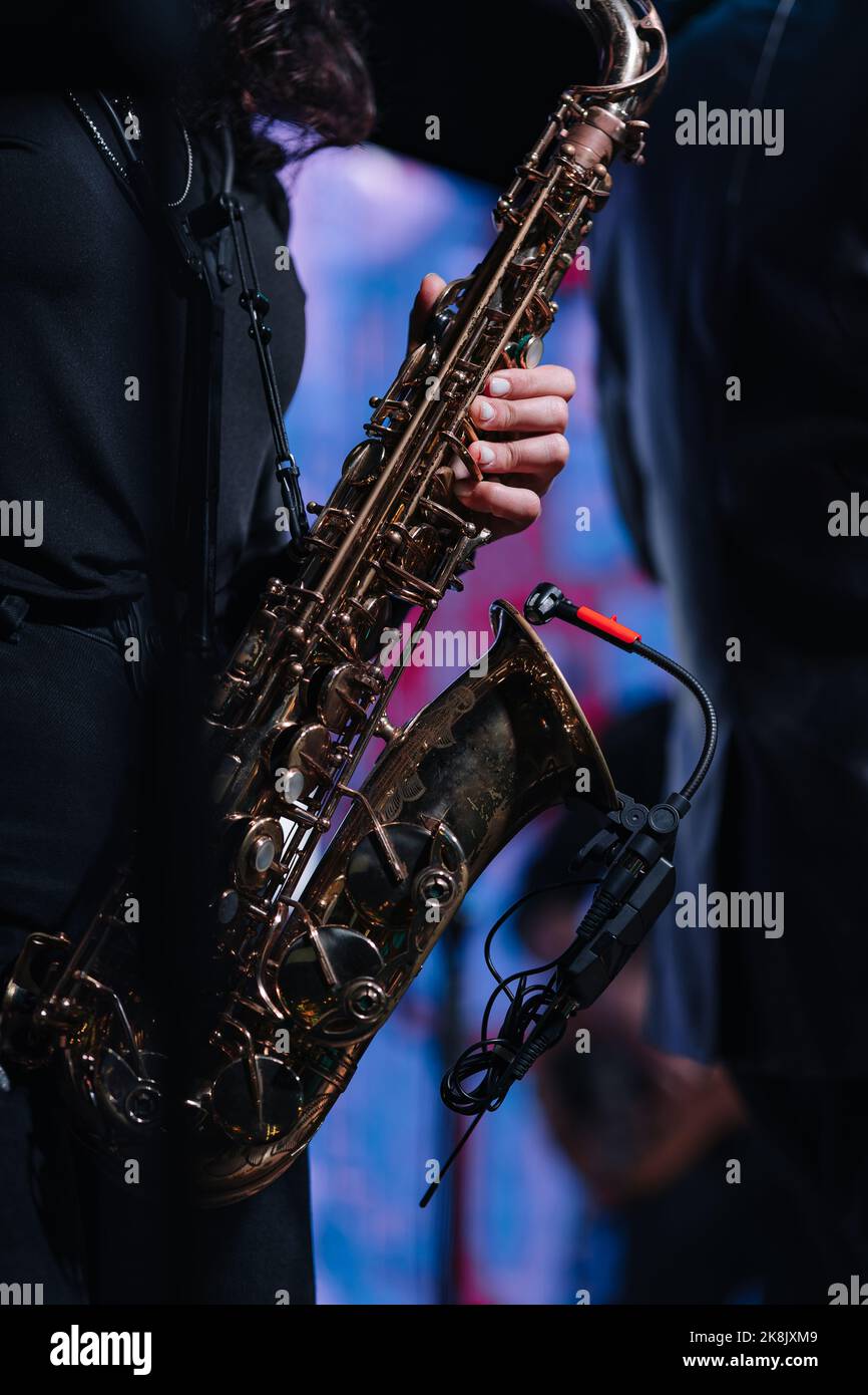 Saxophone soprano dans les mains sur fond sombre. Gros plan sur l'instrument de musique Alto Sax Banque D'Images