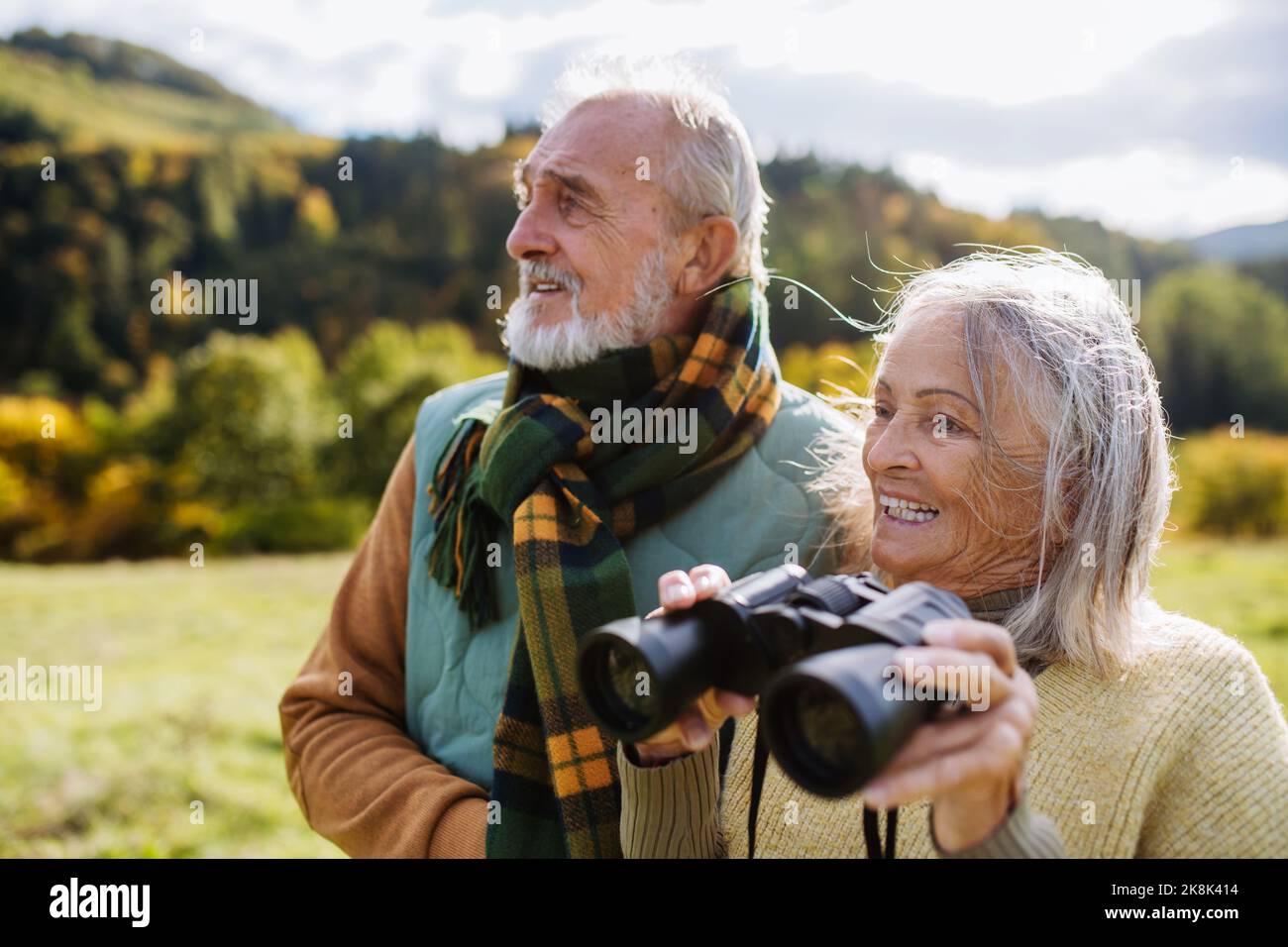 Couple senior regardant la vue à travers des jumelles lors de la marche d'automne. Banque D'Images