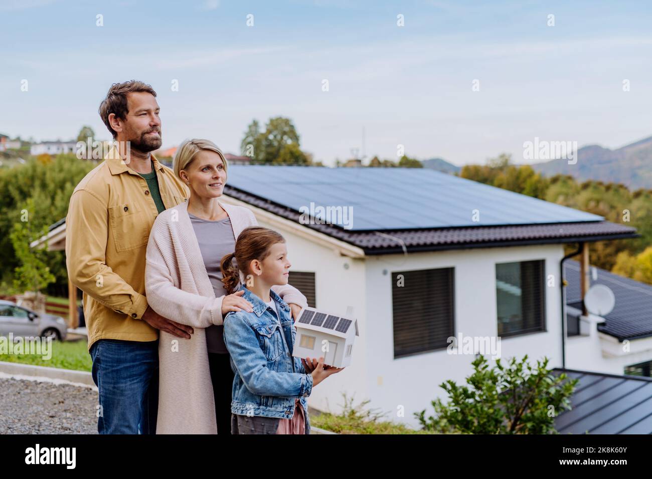 Famille heureuse tenant modèle de papier de la maison avec panneaux solaires.énergie alternative, économie de ressources et concept de style de vie durable. Banque D'Images