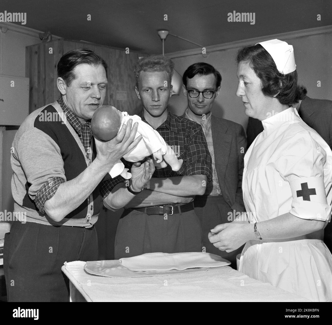 Oslo 1956. Croix-Rouge d'Oslo avec des cours de soins aux nourrissons pour les pères enceintes. Papa apprend la prise. Cours de papa. Soulevez doucement maintenant pour que la tête ne retombe pas ! Le quai d'enseignement est comme les lalalaus dans le cou et le dos comme un nouveau-né jeune. Modification des tables. Photo: Kaare Nymark / actuel / NTB Banque D'Images