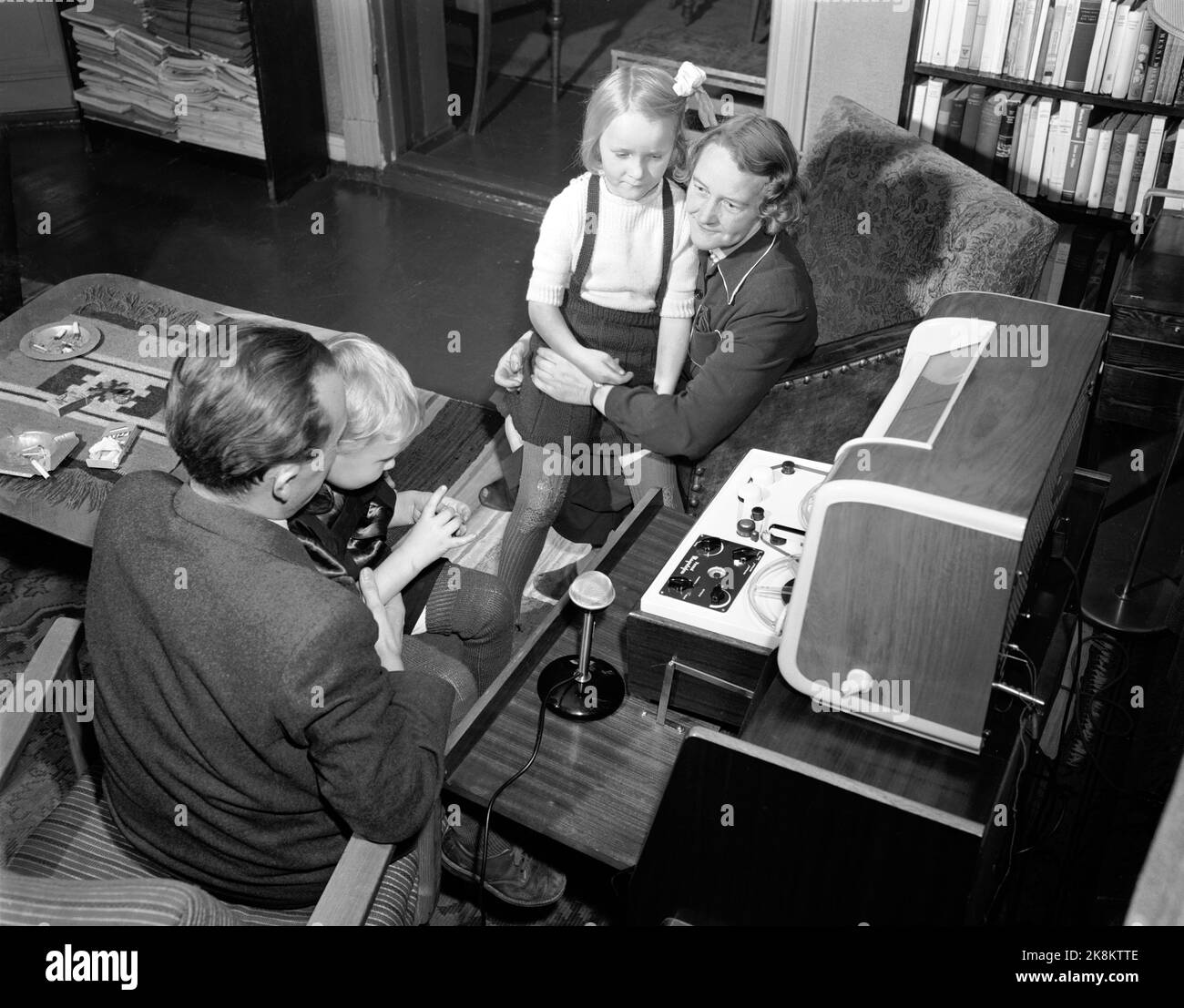 Oslo décembre 1949. Le magnétophone est introduit en Norvège. C'est la société Proton qui a des droits exclusifs sur le nom magnétophone. Plus tard, la machine devient connue sous une variété de noms, tels que les comprimés de ruban, la cassette, l'enregistreur de bande et le lecteur de rinçage. Pouvoir enregistrer et conserver les impressions de la première année des enfants a été le rêve de nombreux parents. Voici une famille avec mère, père et deux enfants qui essaient le lecteur de cassettes dans la maison. Photo: Sverre A. Børretzen / actuel / NTB Banque D'Images