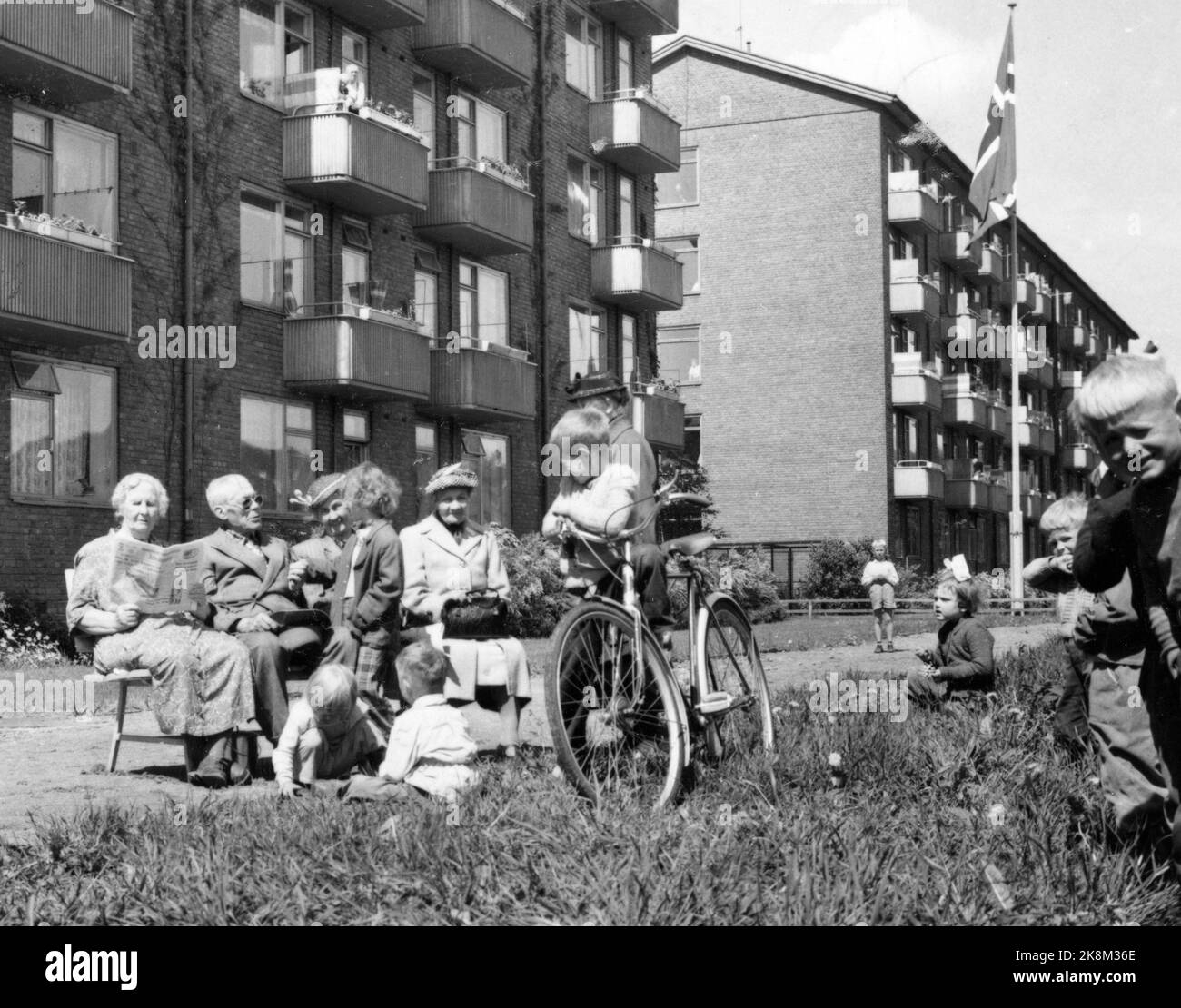 Oslo 1955. Les personnes âgées s'assoient sur des bancs à l'extérieur des blocs d'appartements à 'Trygdeheimen' Elvegløtt, à Bjølsen à Oslo. Ils parlent aux enfants qui jouent. C'est l'été en ville. Une femme âgée lit Arbeiderbladet, un des garçons a un vélo. L'indicateur est hissé sur la tige. Les gens ont vue sur les petits balcons. Photo: Aage Storløkken / actuel / NTB Banque D'Images