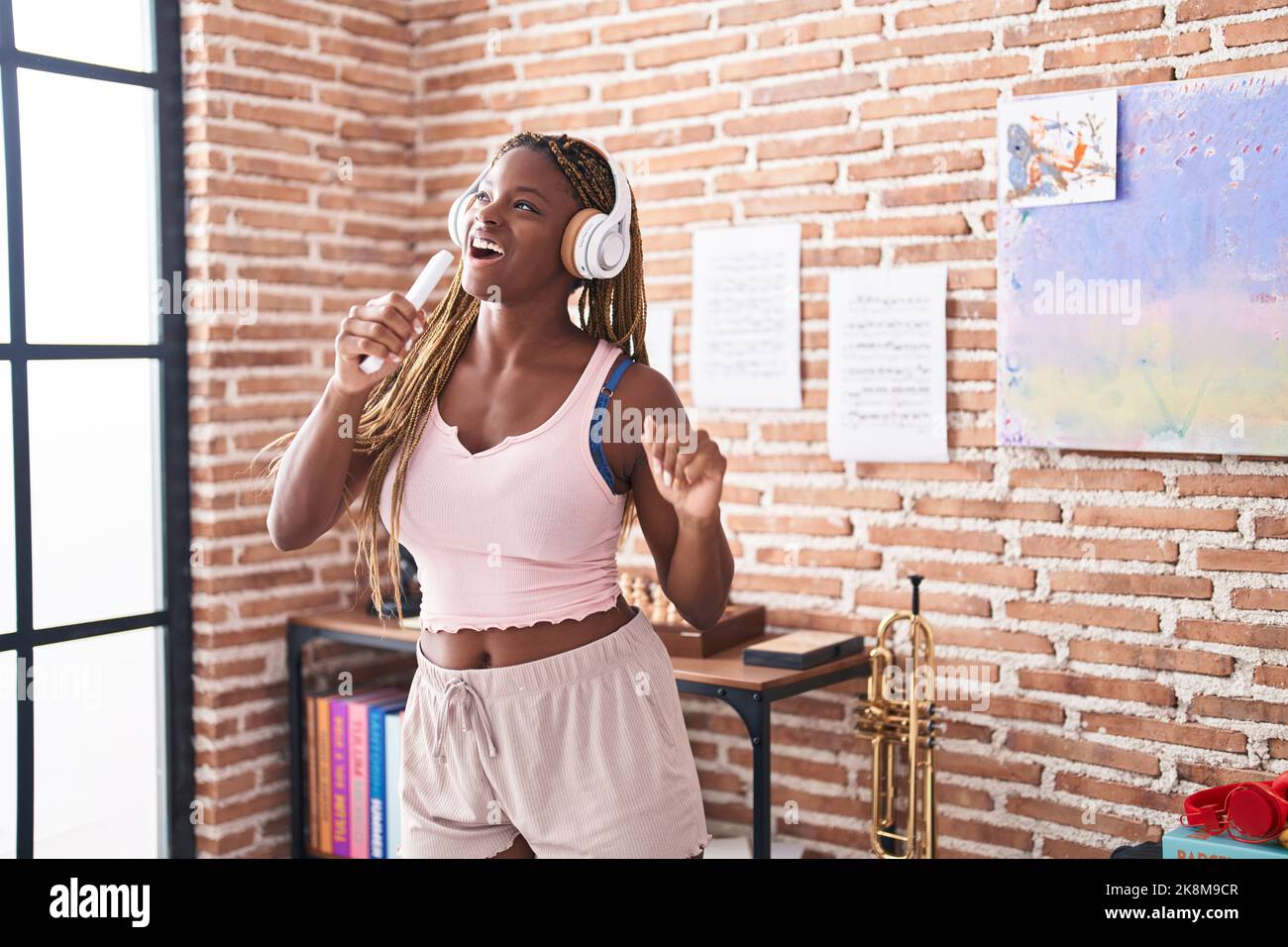 Femme afro-américaine écoutant de la musique chantant à la maison Banque D'Images