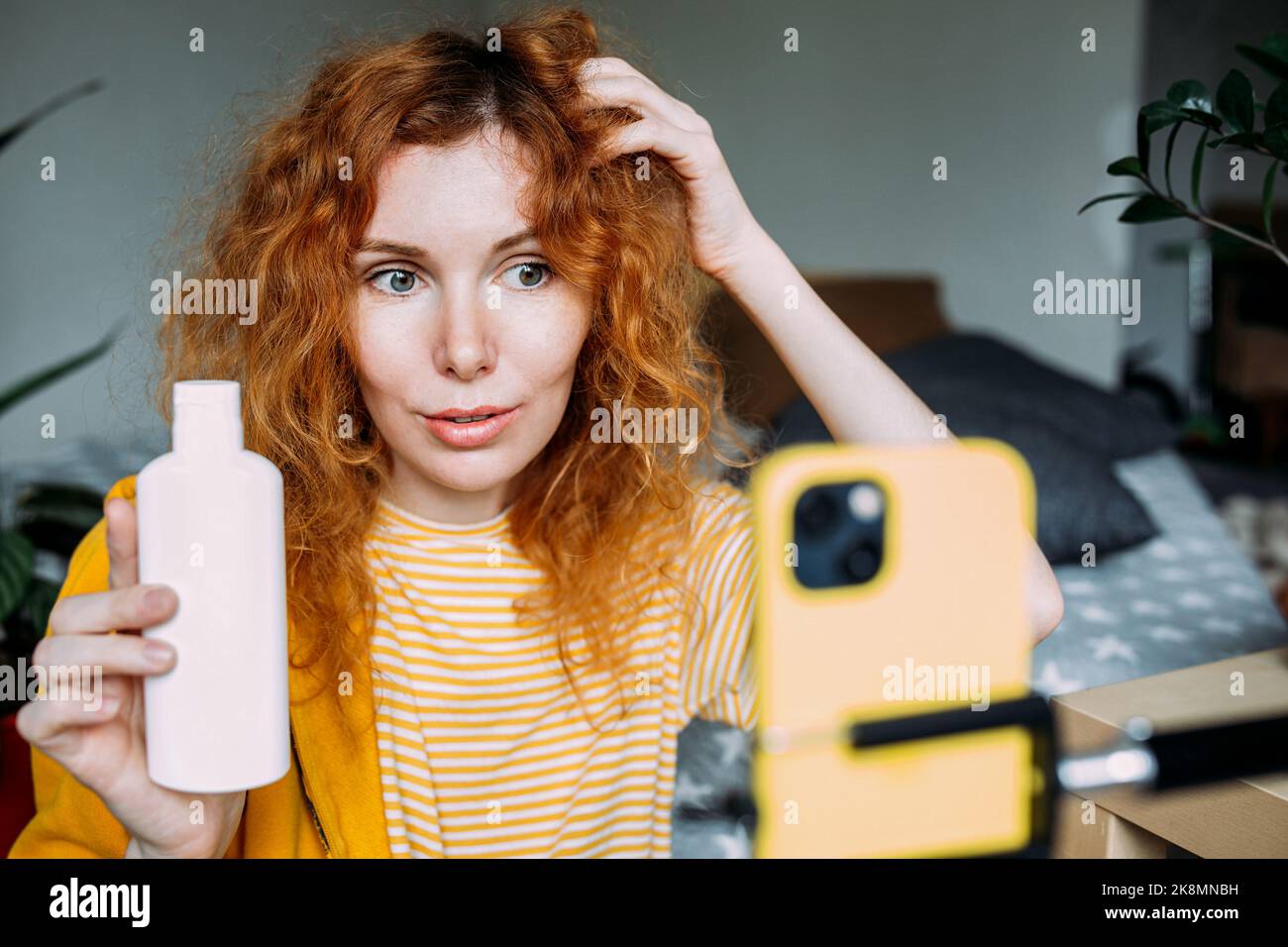 La blogueur de femme à cheveux rouges diffuse des critiques en direct de produits de beauté pour les cheveux Banque D'Images