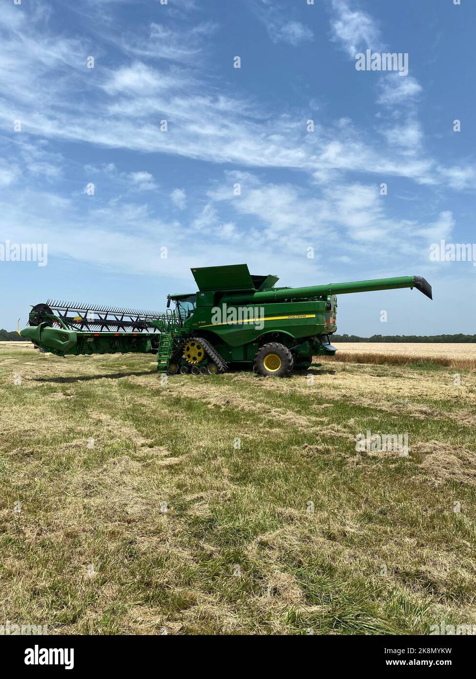 Vue verticale d'une moissonneuse-batteuse John Deere dans le champ sous le ciel bleu Banque D'Images