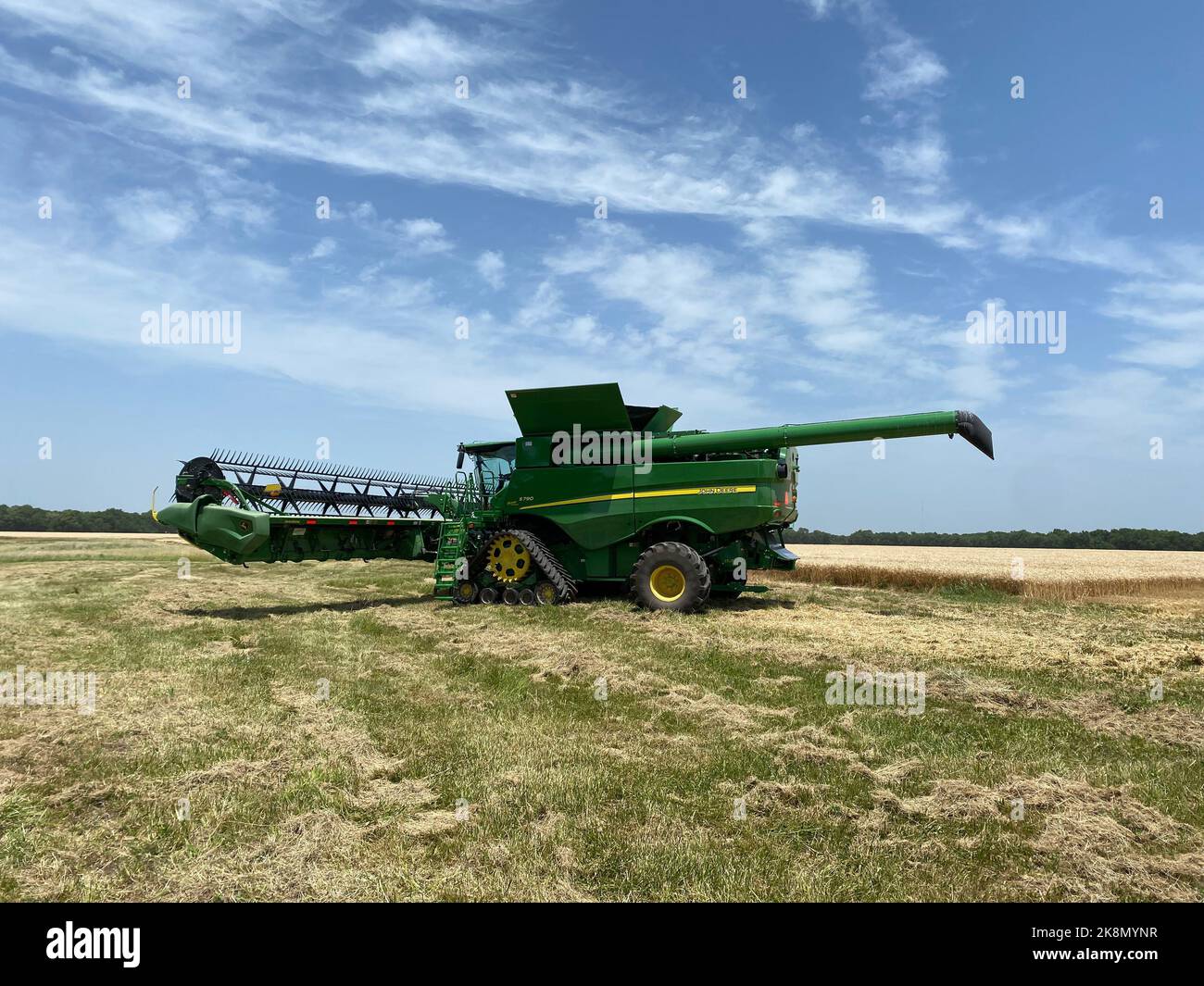 Vue d'une moissonneuse-batteuse John Deere dans le champ sous le ciel bleu Banque D'Images