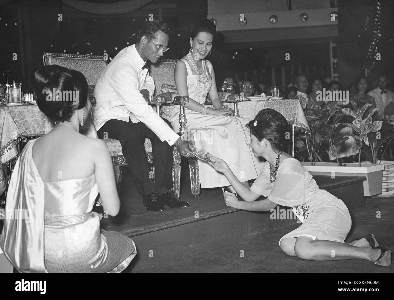 Bangkok 5 juin 1965, Thaïlande. Depuis 5 ans, la compagnie aérienne SAS a construit Thai Airways International Ltd (Thai International) en Thaïlande, pour la joie et le bénéfice mutuels. La société compte trois caravanes et environ 700 employés, dont 37 Scandinaves. Ici, de la fête de 5 ans à laquelle le couple royal thaïlandais a participé, ils distribuent une victoire ici, un billet touristique reçu par le gagnant d'une manière soumise. C'est le roi Phumiphol Adalyadeij qui donne le billet, la reine Sirikit regarde avec un joli sourire. Photo: Sverre A. Børretzen / actuel / NTB Banque D'Images