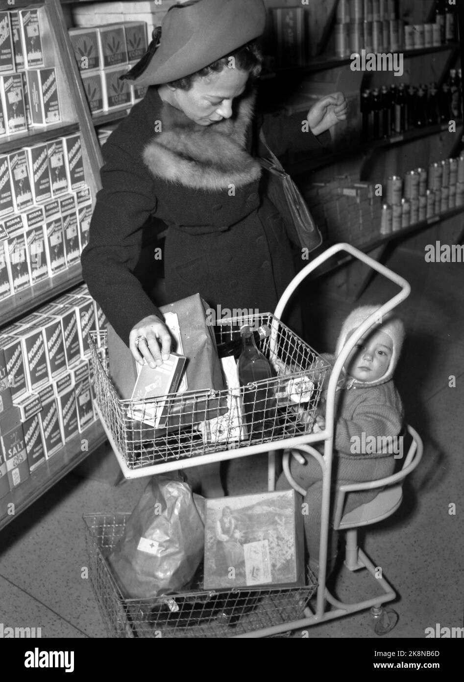 Oslo 1947 : le rationnement des marchandises a duré longtemps après la guerre. Voici une jeune mère qui visite la première boutique libre-service d'Oslo avec son enfant qui a eu un chariot pour s'asseoir sur le chariot, tandis que la mère peut marcher le long des étagères elle-même et choisir les marchandises dont elle a besoin. Les marchandises sont emballées, le prix et la valeur de la marque sont sur l'emballage. Ici avec un panier avec de la nourriture. Association nationale coopérative norvégienne 'Snarkjøp' Samvirkelag in Parkveien 65. Photo : Th. Scotaam / courant / NTB Banque D'Images