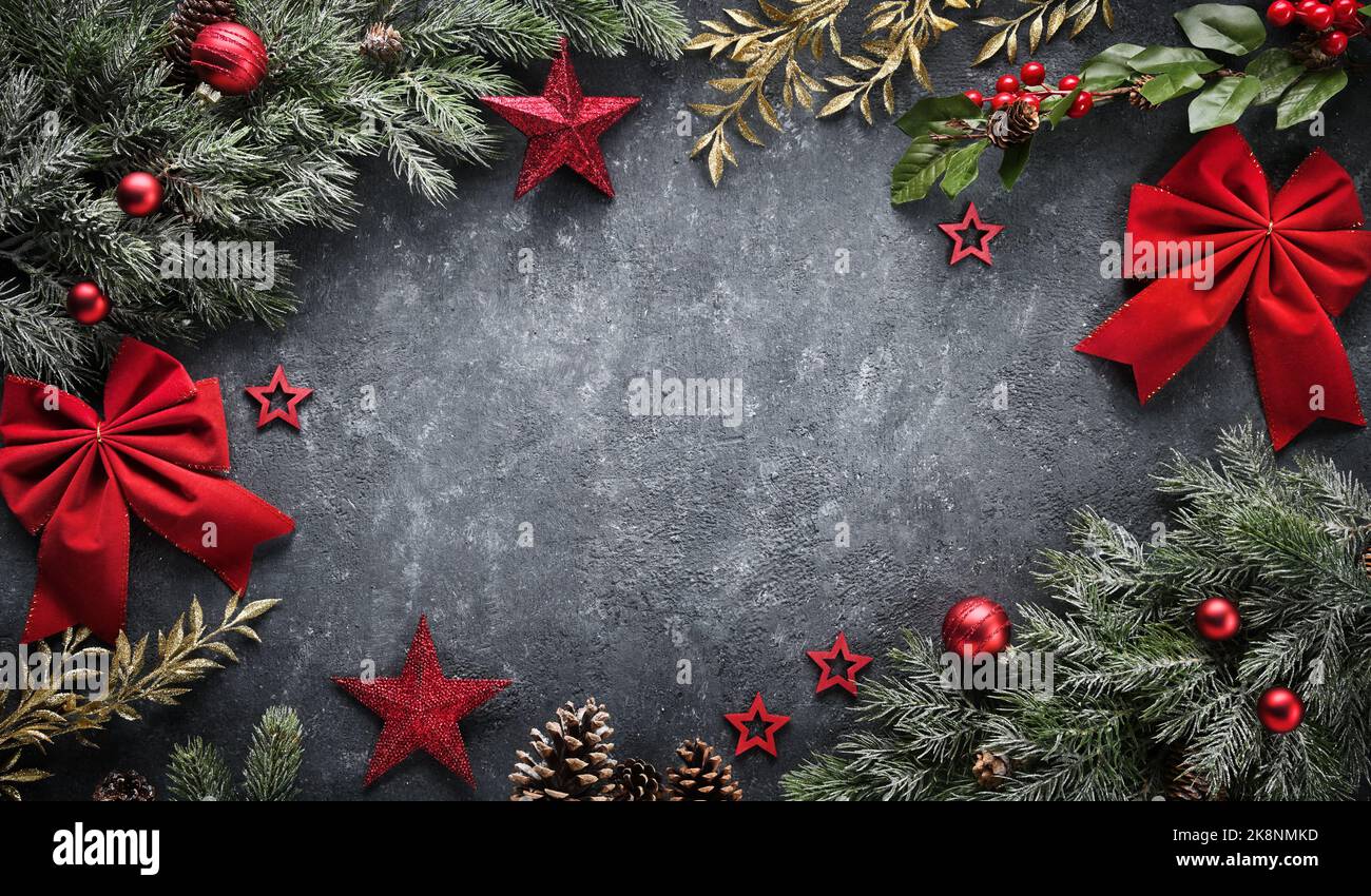Fond de Noël avec texture grise grossière au milieu comme espace de copie, encadré de branches et ornements rouges Banque D'Images