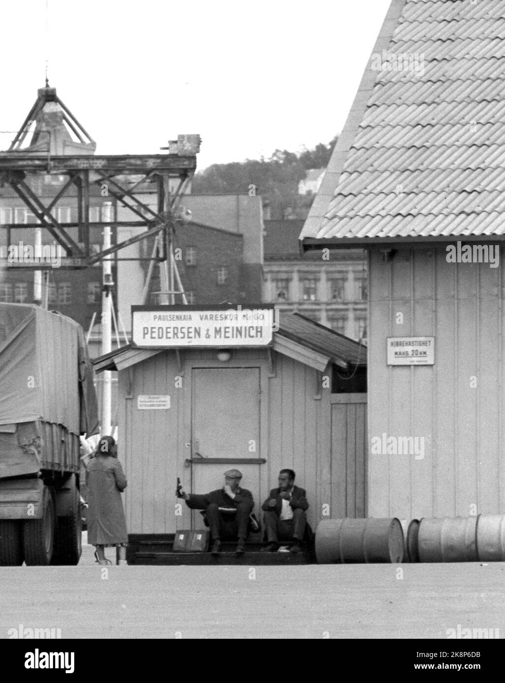 Oslo à l'été 1962. Une promenade le long de l'Akerselva de OS à OS. Au hangar n° 60 de Pedersen et Meinich sur le quai à 'Køla-Pålsen' (officiellement Paulsenkaia), deux travailleurs ont trouvé un endroit où ils peuvent manger la boîte à lunch et partager une bouteille, et ils sont heureux de partager une dame qui passe aussi .. Photo: Åge Storløkken / actuel / NTB. Lok physique: Actuel 1962 No. 37: Akerselva, vous avez vieux vous gris. Banque D'Images