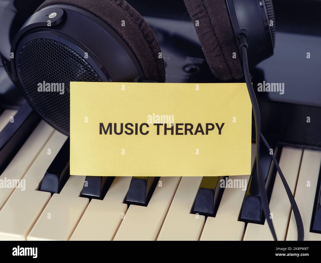 Une note en papier jaune avec les mots Music Therapy sur un piano avec un casque derrière lui. Gros plan. Banque D'Images