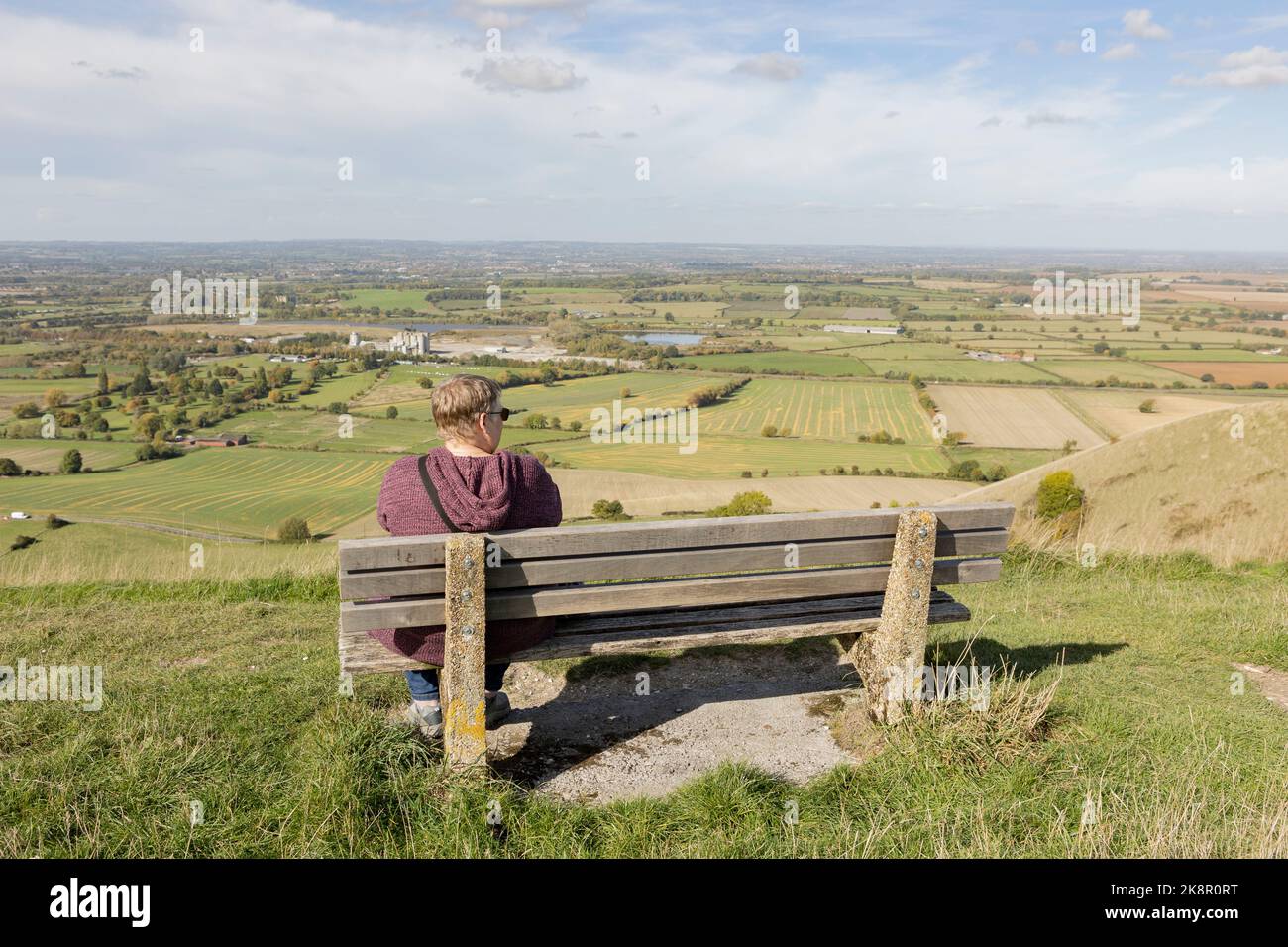 femme assise seule sur un banc surplombant un paysage anglais spectaculaire Banque D'Images