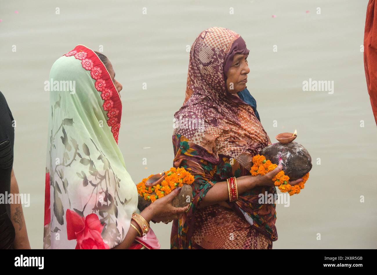 Des hommes et des femmes indiens non identifiés prient et consacrent pour le festival Chhath Puja sur le côté du fleuve Ganges à Varanasi, Inde. Banque D'Images
