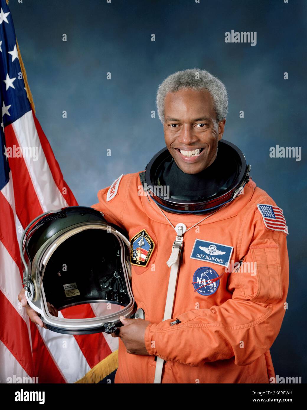 Portrait officiel de l'astronaute Guion S. Bluford. Bluford, membre de la classe 8 de l'astronaute et de la United States Air Force (USAF), pose dans son costume de lancement et d'entrée (LES) tenant un casque de lancement et d'entrée (LEH) avec le drapeau des États-Unis comme toile de fond. Banque D'Images