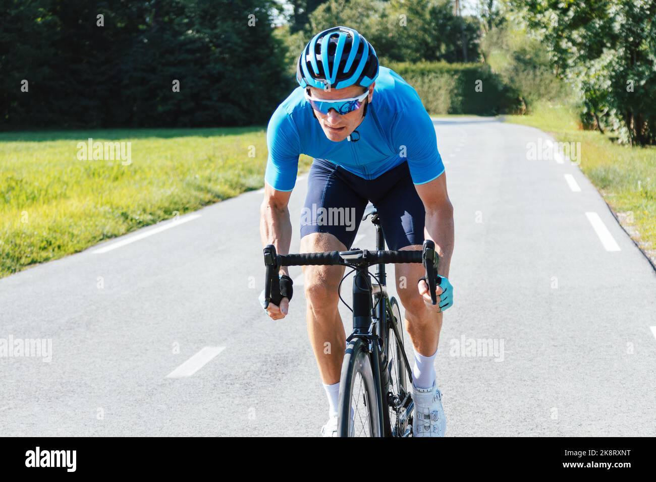 Coureur professionnel de vélo de route mâle prenant une position aérodynamique de corps pour le sprint sur un vélo, vue avant. Banque D'Images