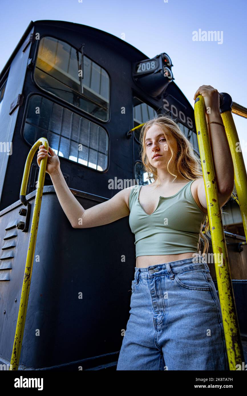 Jeune femme debout sur l'escalier d'un moteur électrique diesel de train Banque D'Images