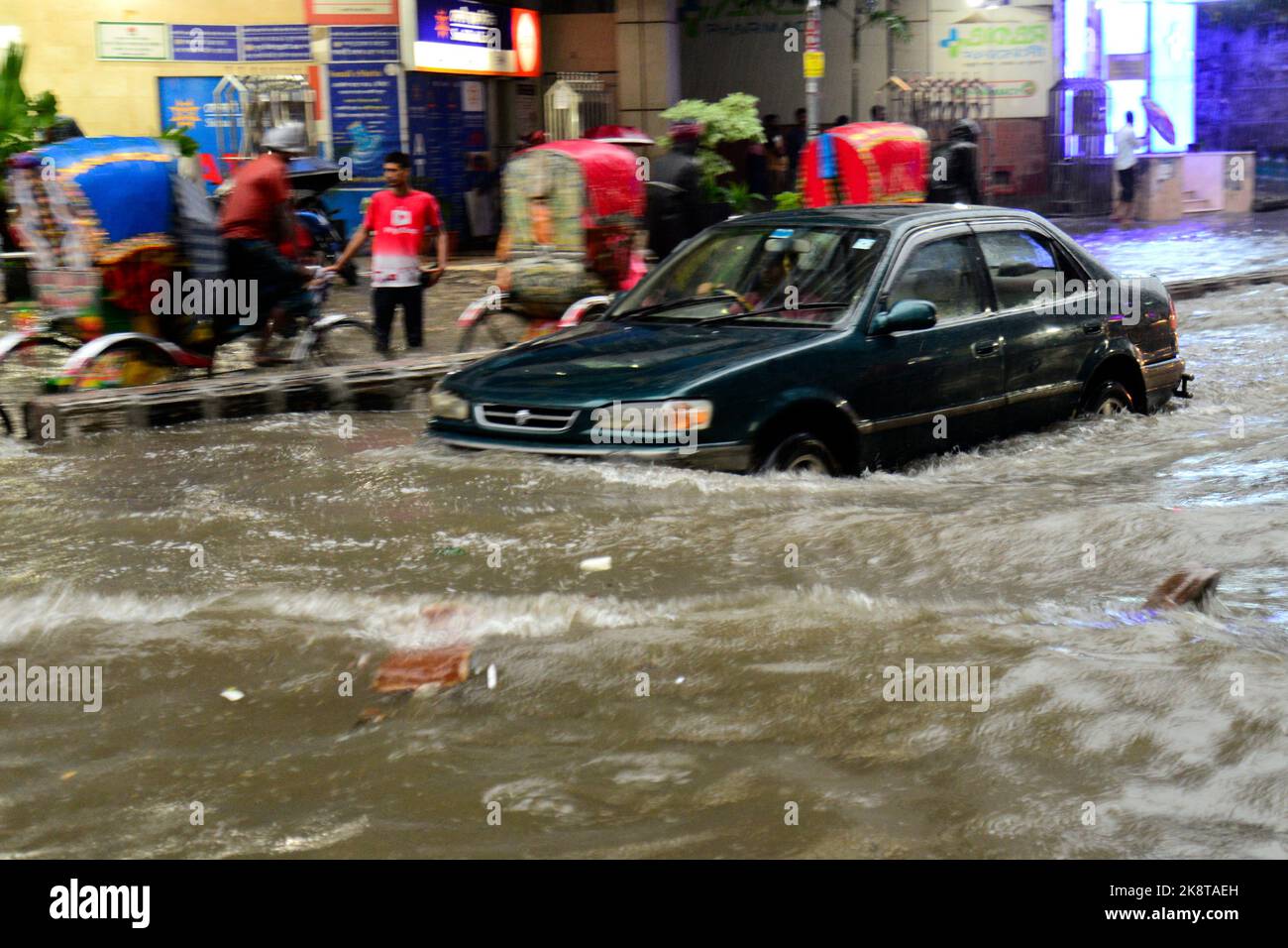 Des véhicules et des rickshaws tentent de conduire avec des passagers à travers les rues pavées de Dhaka de fortes pluies ont provoqué l'impact du puissant cyclone Sitrang, à Dhaka, au Bangladesh, sur 24 octobre 2022. Banque D'Images