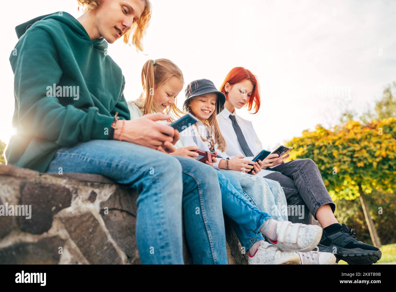 Un adolescent et une fille sœur enfants assis et parcourant leur smartphone. Un jeune temps insouciant et une image de concept de technologie moderne Banque D'Images