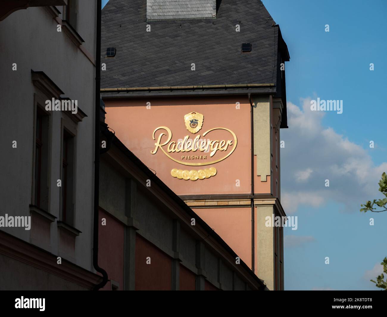 Bâtiments de la brasserie Radeberger avec un grand logo doré sur la façade. La lumière du soleil illumine le panneau sur le mur extérieur de l'entreprise. Banque D'Images