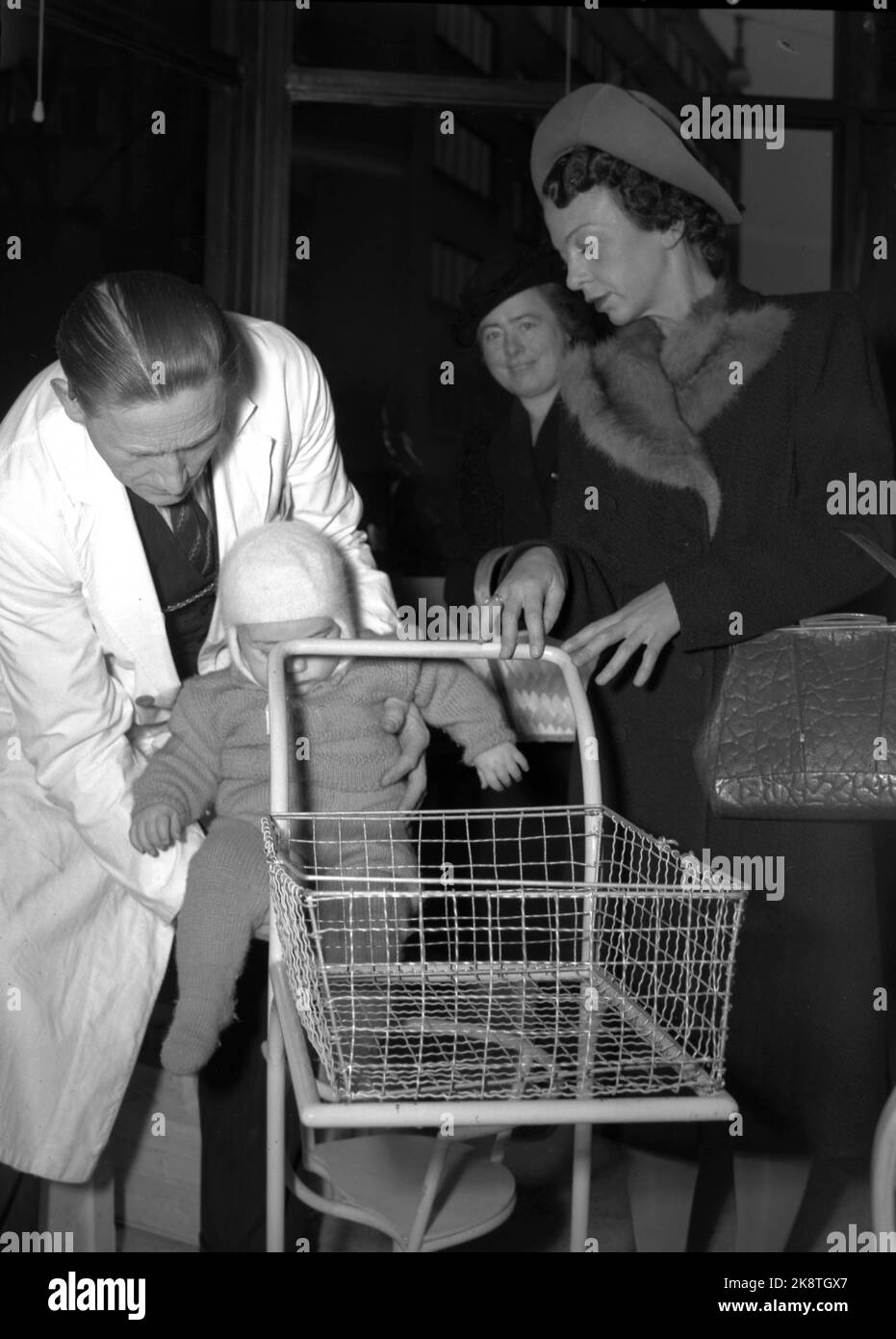 Oslo 1947 : le rationnement des marchandises a duré longtemps après la guerre. Voici une jeune mère qui visite la première boutique libre-service d'Oslo avec son enfant qui reçoit l'aide de l'employé dans un chariot dans le chariot, tandis que la mère peut marcher le long des étagères elle-même et ramasser les marchandises dont elle a besoin. Les marchandises sont emballées, le prix et la valeur de la marque sont sur l'emballage. Association nationale coopérative norvégienne 'Snarkjøp' Samvirkelag in Parkveien 65. Photo : Th. Scotaam / courant / NTB Banque D'Images