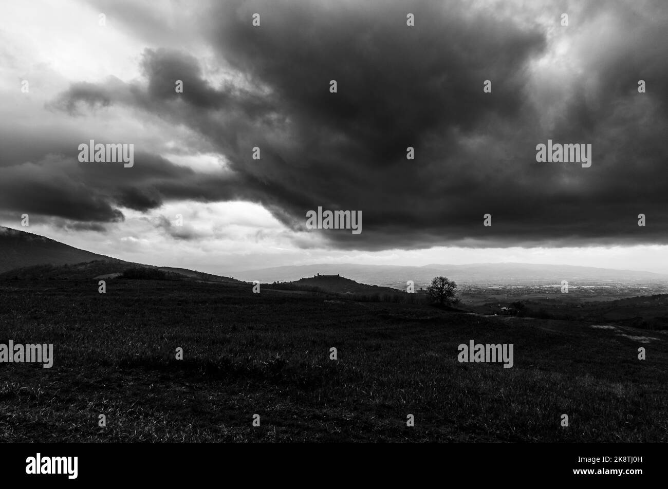 Vue lointaine d'Assise Ombrie Italie sous moody, nuages menaçants Banque D'Images