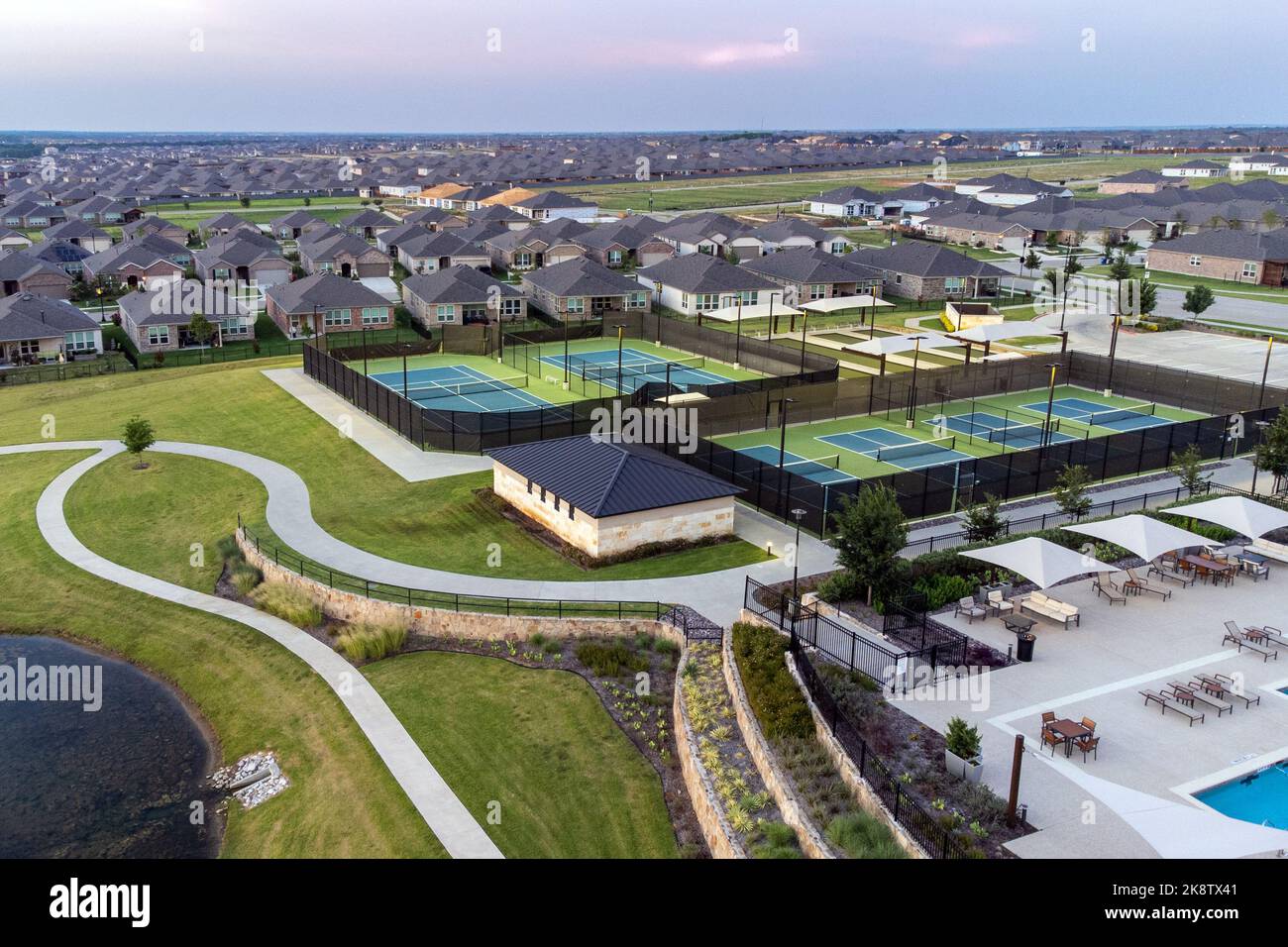 Vue aérienne des grands courts de tennis, piscine au centre de loisirs communautaire avec des demeures avec des zones de salon en plein air en été. Banque D'Images