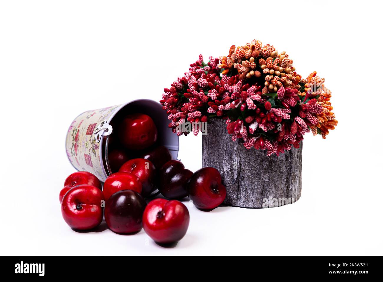 Un gros plan de vase en bois avec des fleurs et des pommes rouges et blanches. Le vase en porcelaine a une surface cannelée. Le vase avec un bouquet est isolé contre Banque D'Images