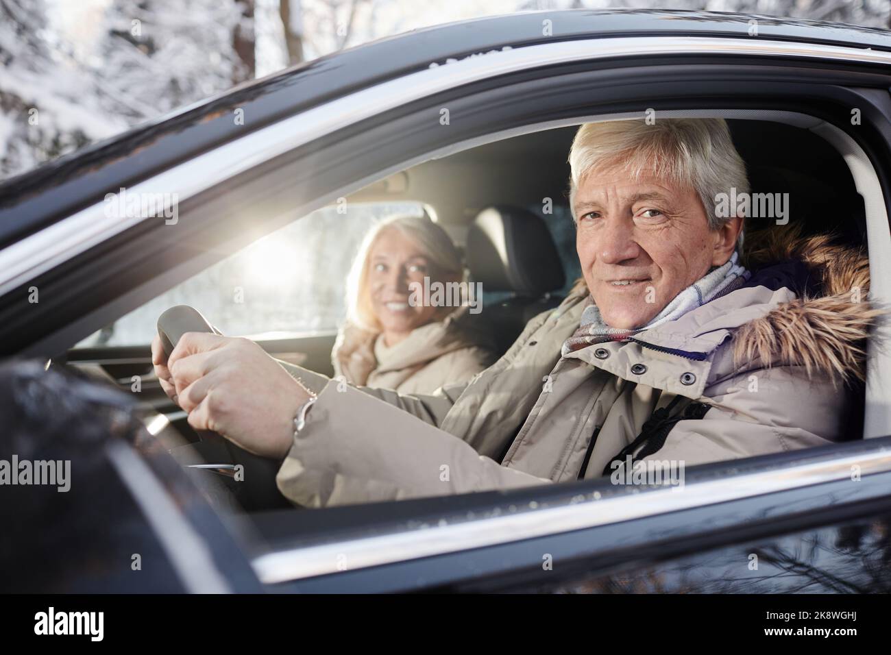 Portrait d'un couple senior joyeux conduisant une voiture en hiver, concentrez-vous sur l'homme senior derrière le volant, regardant l'appareil photo, l'espace de copie Banque D'Images