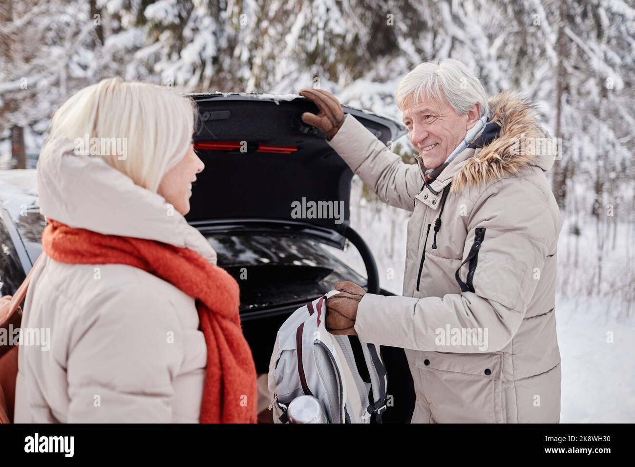Portrait de couple senior souriant ouvrant le coffre de voiture tout en appréciant une escapade hivernale dans la nature ensemble, espace de copie Banque D'Images