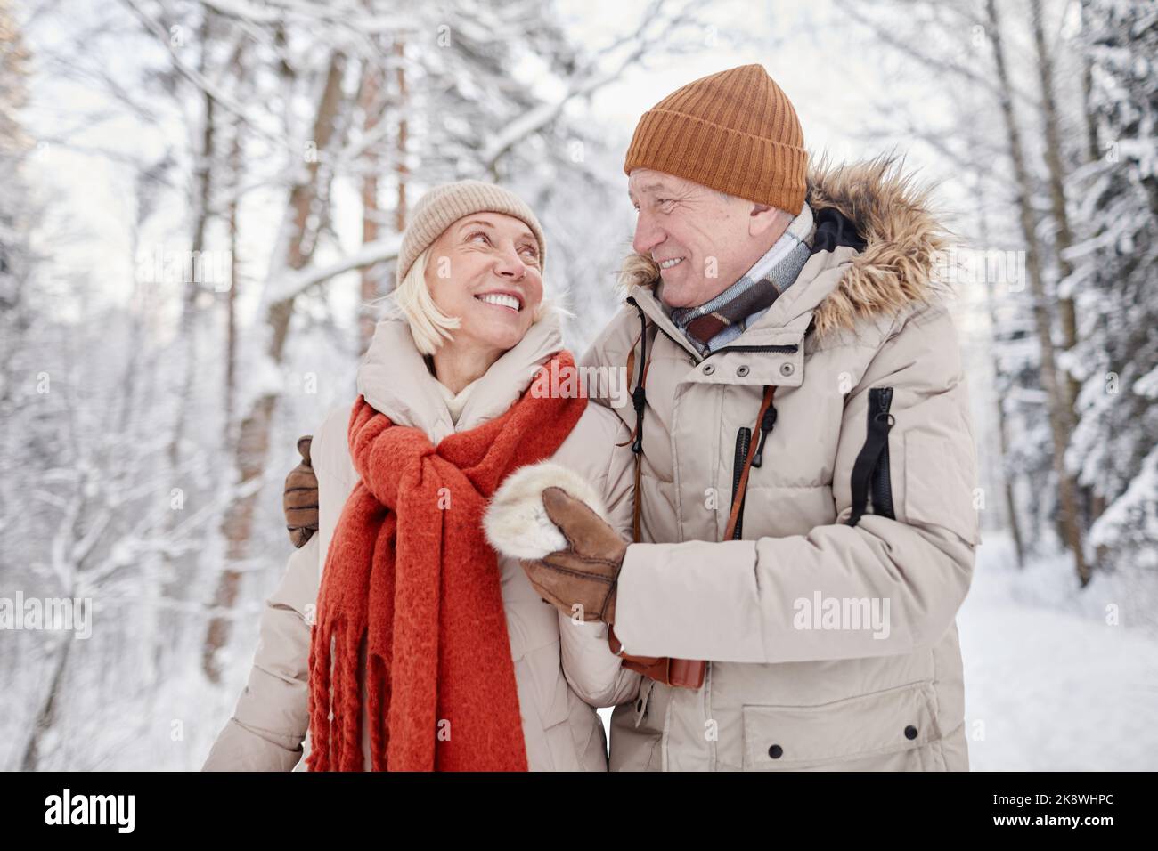 Portrait de la taille vers le haut de couple heureux de personnes âgées en appréciant la promenade dans la forêt d'hiver et regardant l'un l'autre avec amour Banque D'Images