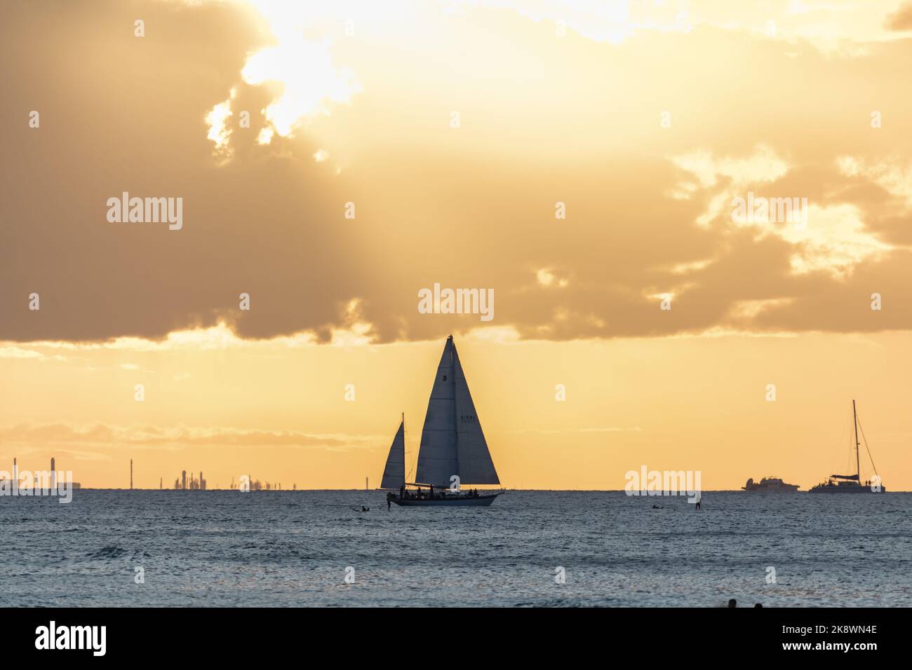Superbe coucher de soleil au départ d'Oahu à Hawaï avec silhouettes de surfeurs et nageurs. Banque D'Images