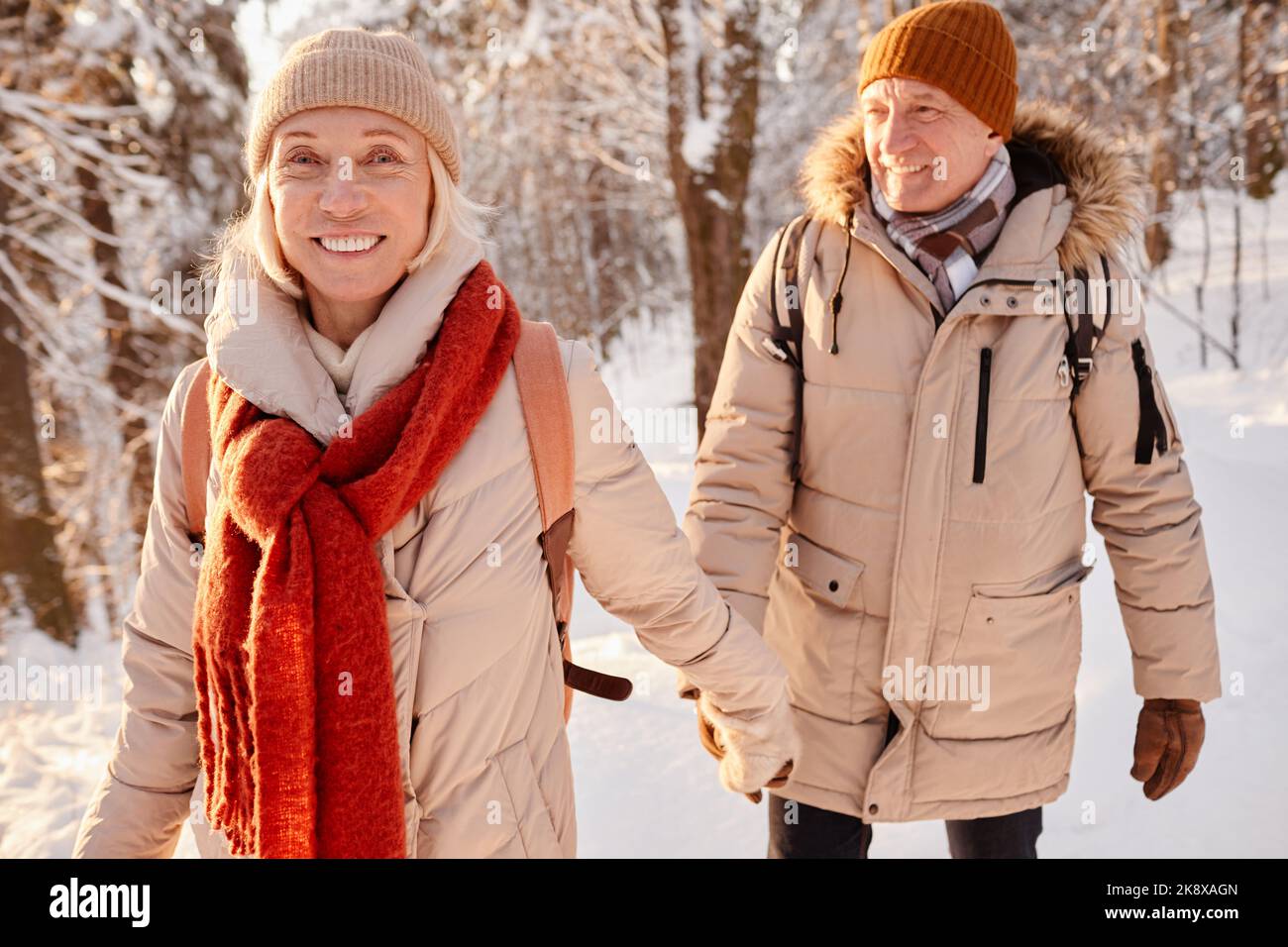Portrait à la taille du couple senior heureux en profitant de la promenade dans la forêt d'hiver et en tenant les mains Banque D'Images