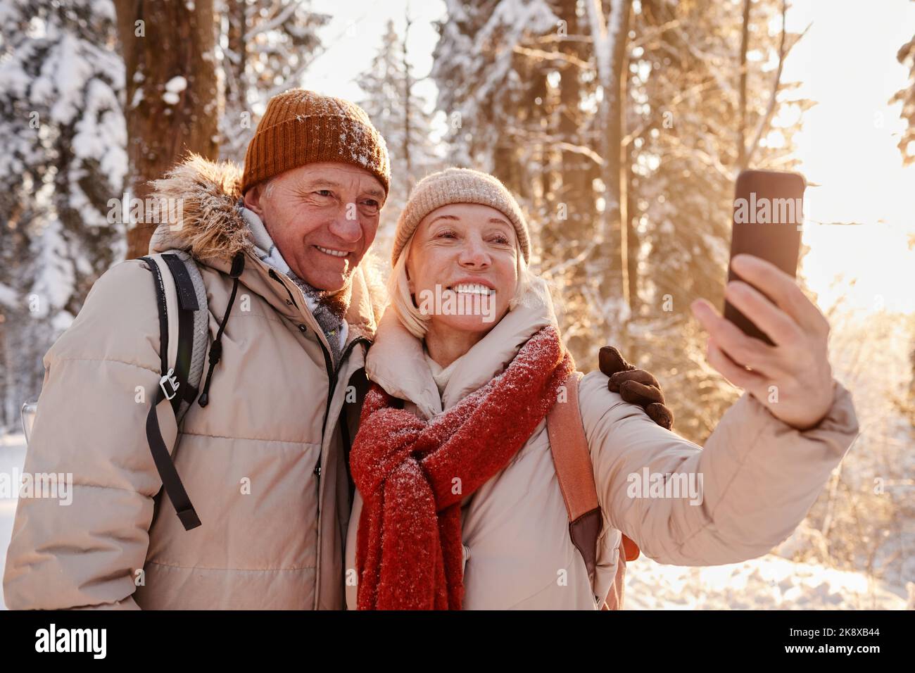 Portrait à la taille du couple heureux d'âge mûr prenant la photo de selfie tout en appréciant la randonnée dans la forêt d'hiver, l'espace de copie Banque D'Images