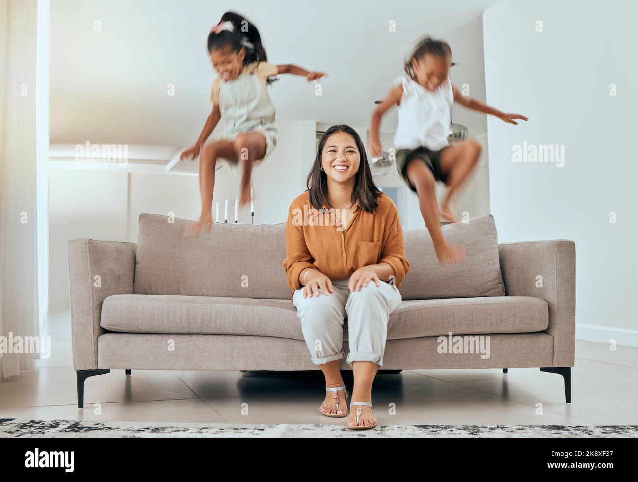 La famille, la mère et les enfants sautant sur le canapé en s'amusant, énergique et hyper à la maison. Bonheur, joie et portrait de mère assis avec des enfants excités saut Banque D'Images