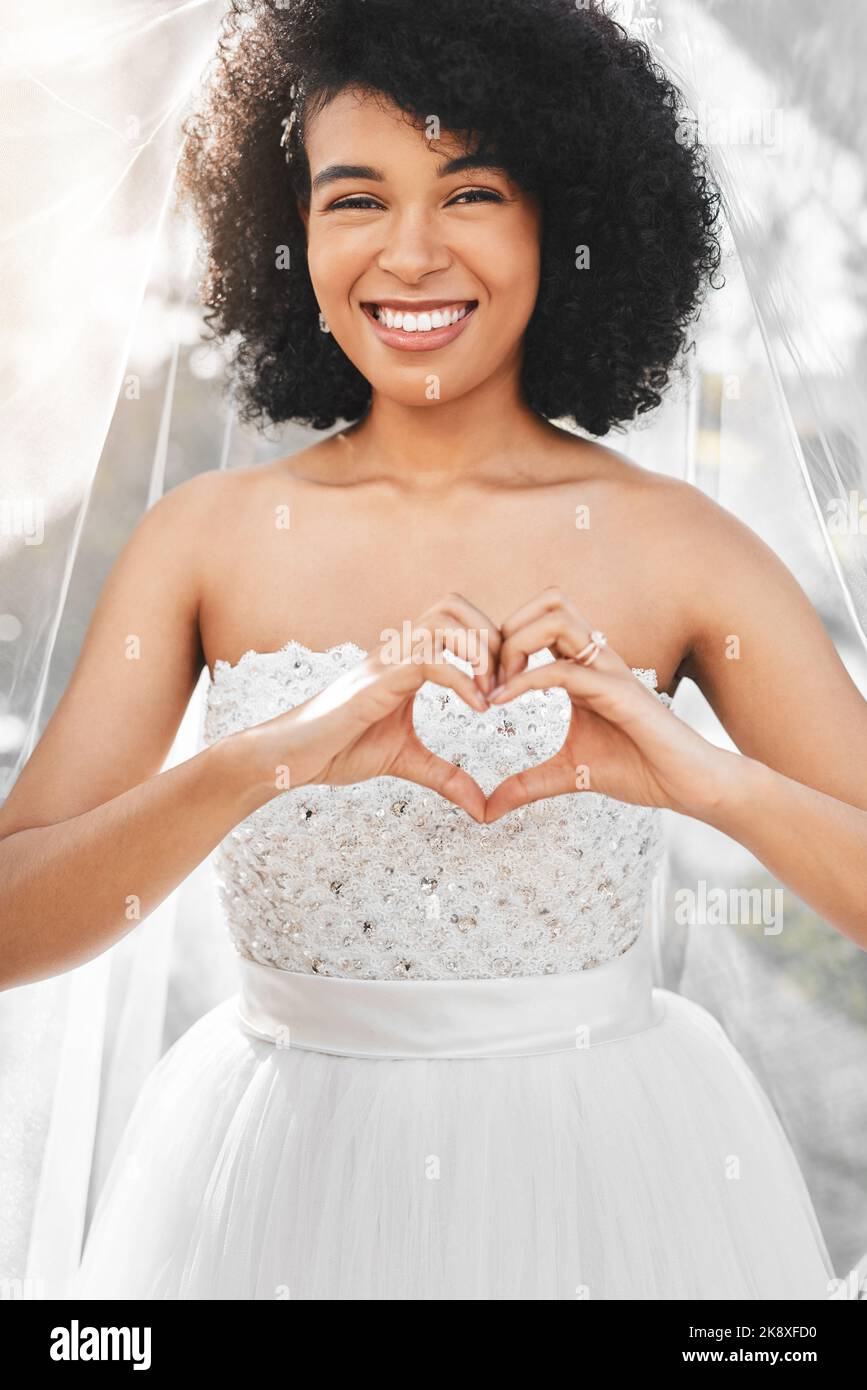 Célébraient le vrai amour aujourd'hui. Portrait d'une jeune mariée heureuse et belle en forme de coeur avec ses mains à l'extérieur le jour de son mariage. Banque D'Images