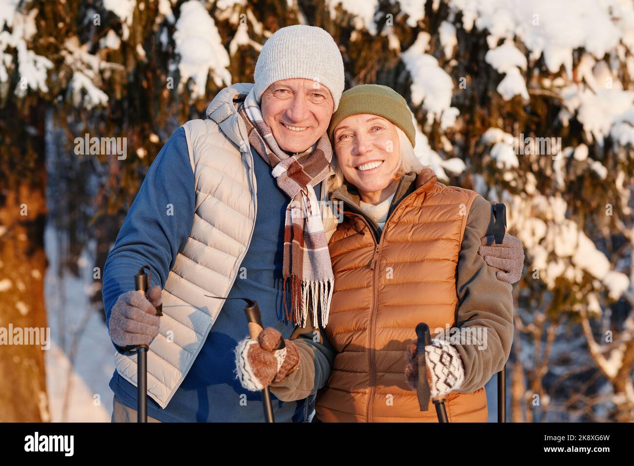 Portrait à la taille du couple heureux senior regardant l'appareil photo tout en randonnée dans la forêt d'hiver ensemble Banque D'Images