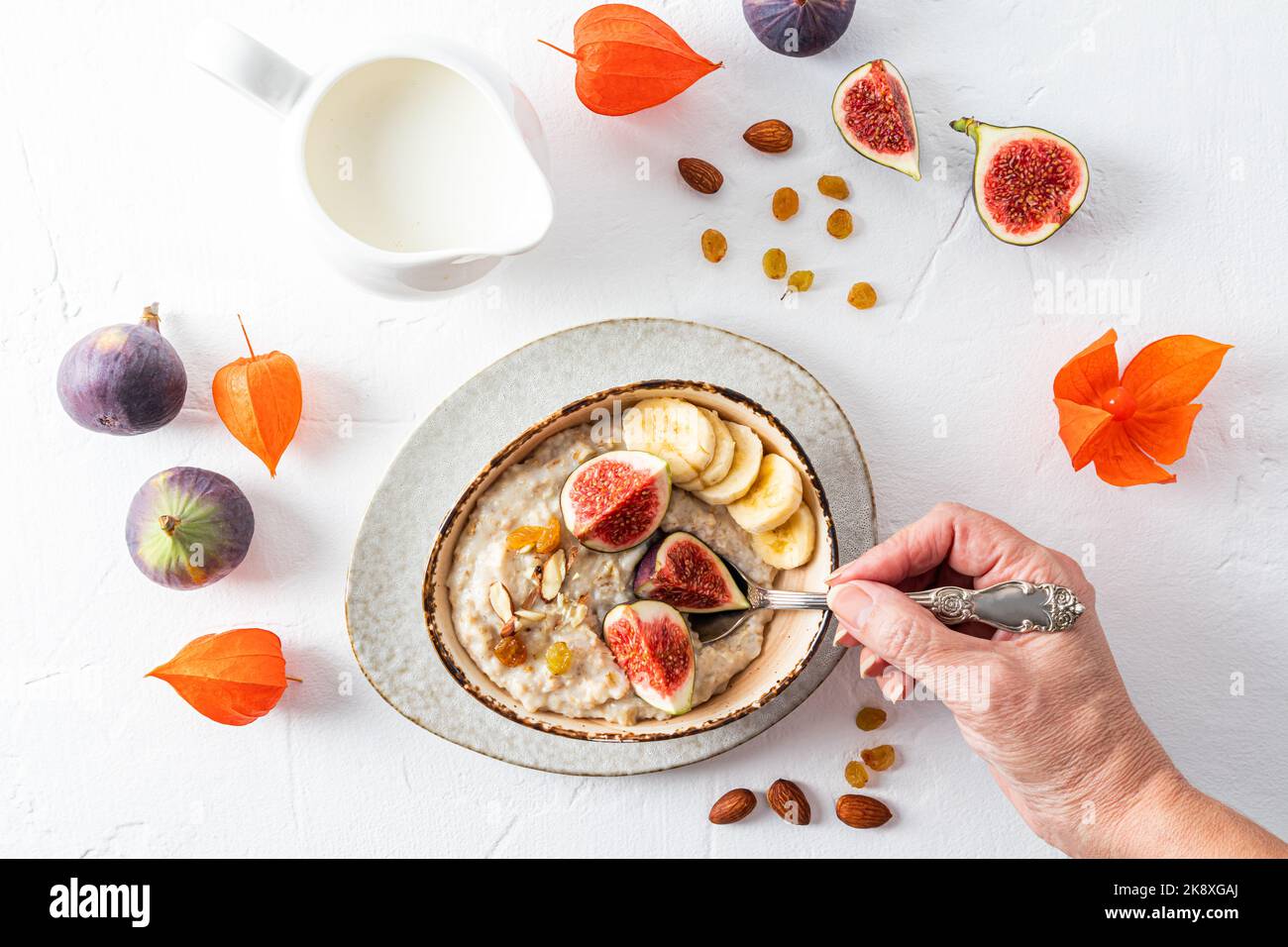 une main de femme tient une cuillère remplie de flocons d'avoine pendant le petit déjeuner. flocons d'avoine avec des fruits dans un bol. alimentation saine. Détox Banque D'Images