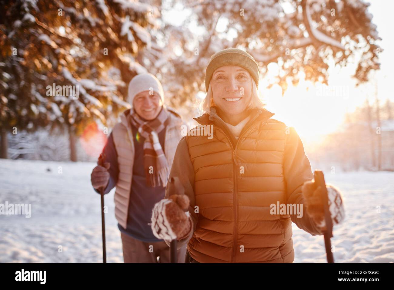 Portrait d'un couple mûr souriant en train de se promener dans la forêt d'hiver au coucher du soleil Banque D'Images