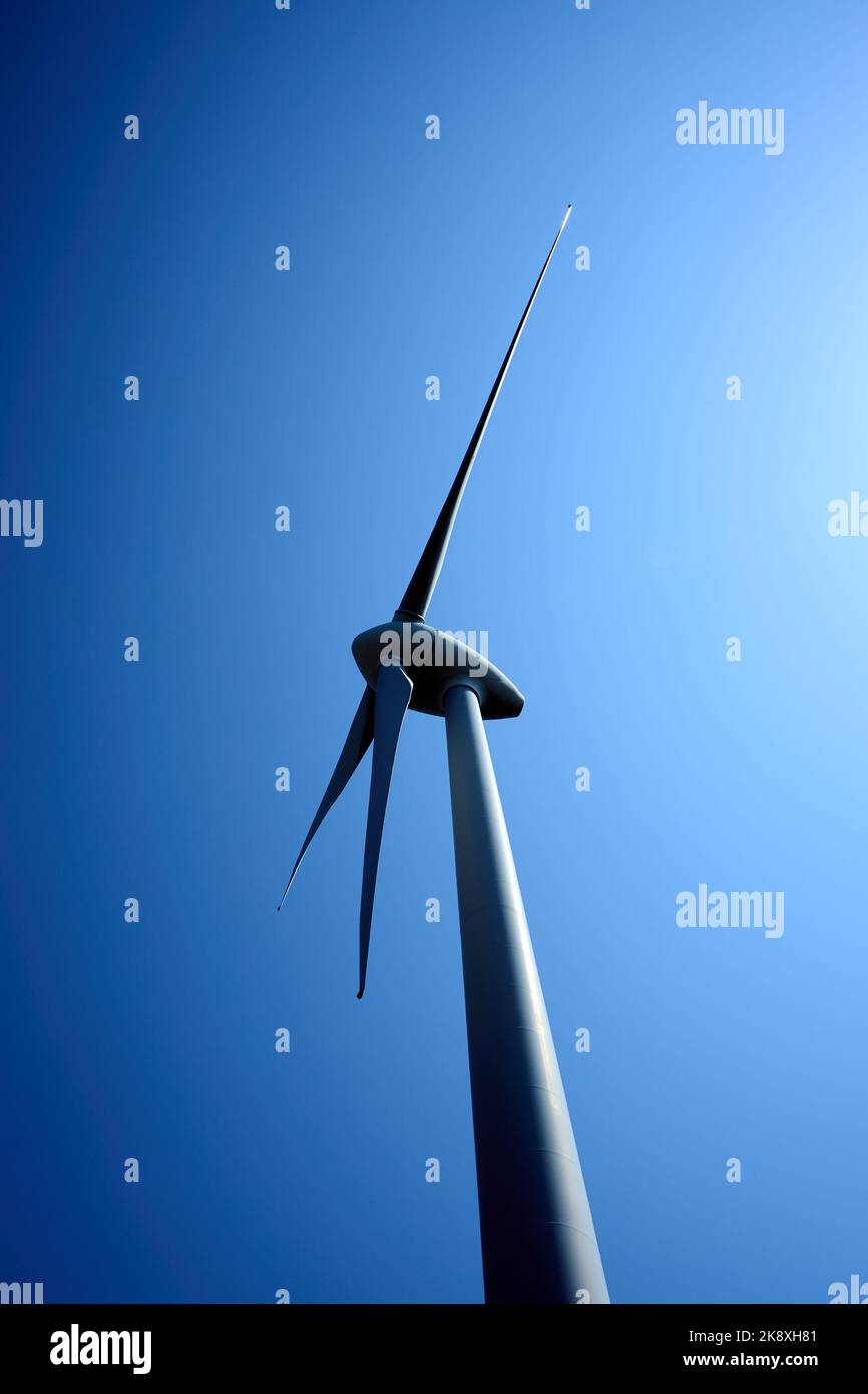 Un plan vertical d'une éolienne avec des pales en rotation par jour ensoleillé Banque D'Images