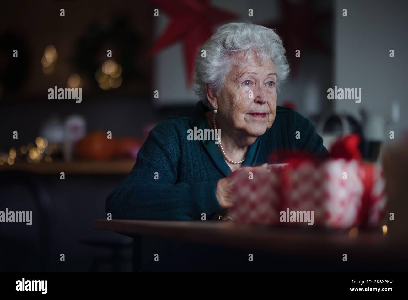 Femme âgée malheureuse assise seule et attendant sa famille pendant la veille de Noël.concept de solitude, de santé mentale et de sénior. Banque D'Images