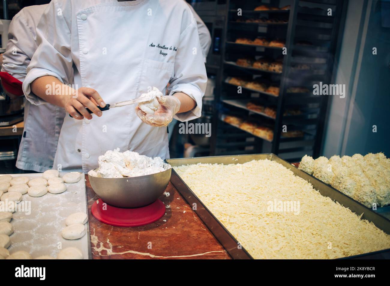 Le maître chocolatier prépare une bombe à la crème meringue recouverte de flocons de chocolat blanc dans la maison du chocolat artisanal à Bruge, en Belgique Banque D'Images