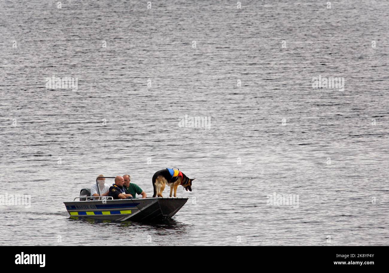 La police cherche une personne disparue, ici elle cherche un lac avec un bateau et un chien de détection de police. Banque D'Images