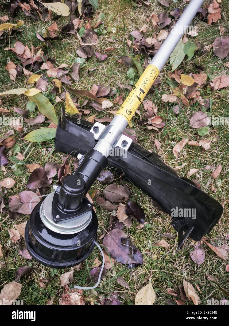 Appareils ménagers: Tondeuse-tondeuse pour tondre les pelouses . Présenté sur un fond d'herbe et de feuilles, vue de face, espace de copie Banque D'Images