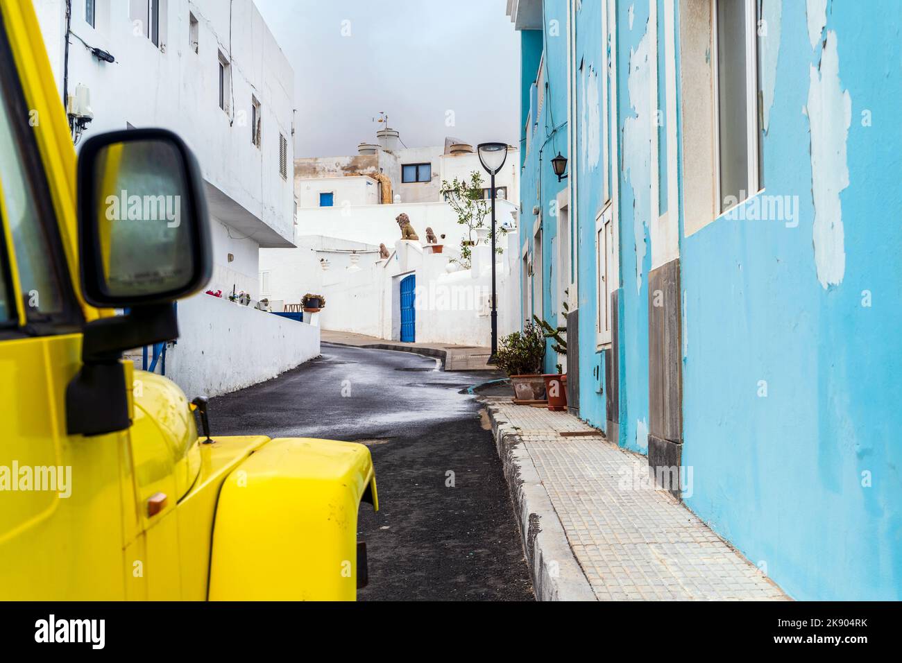 Voiture jaune à 4 roues sur une rue étroite avec des bâtiments blancs et bleus à Corralejo, Lanzarote, îles Canaries, Espagne Banque D'Images
