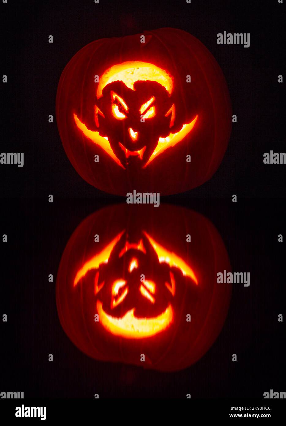 Citrouille sculptée avec un design de visage dracula éclairé dans le noir avec une réflexion supplémentaire - citrouille sculptée - Jack O Lantern pour Halloween Banque D'Images