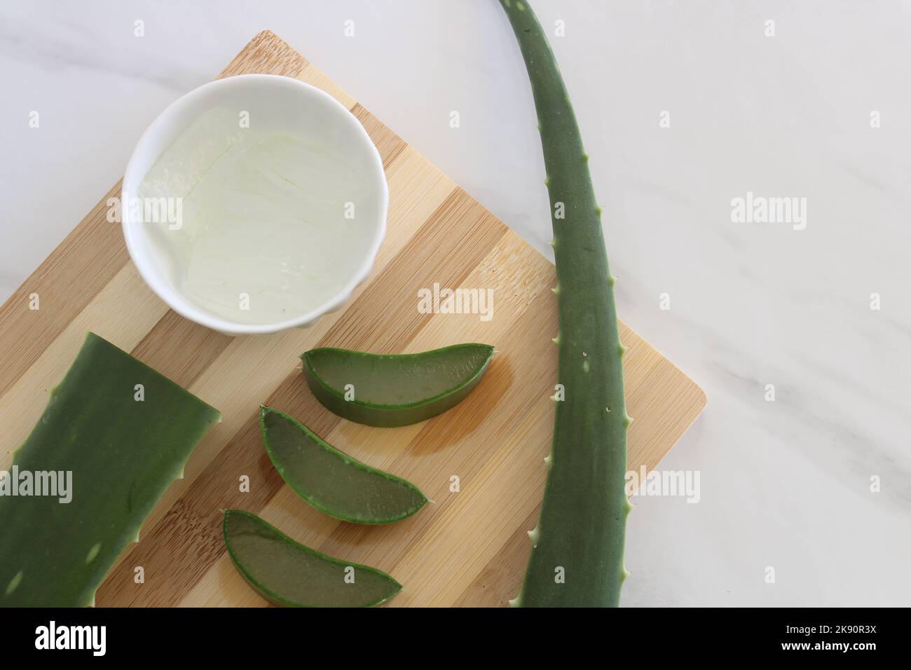 Morceaux de vera d'aloès et un bol de gel de vera d'aloès sur la planche à découper. Banque D'Images