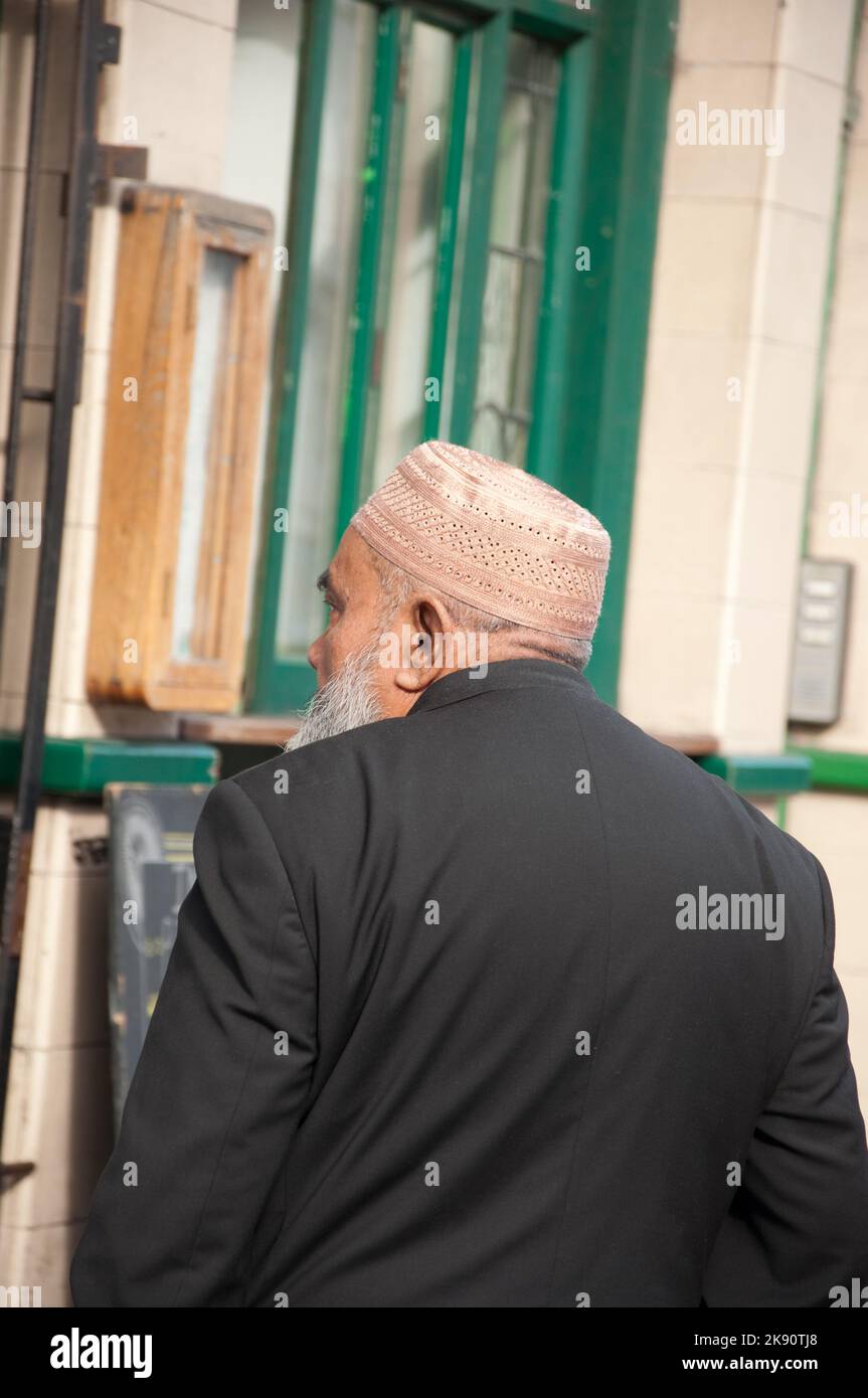 Homme au chablcap arabe marchant le long de Whitechapel, Tower Hamlets, East End, Londres - il y a un grand nombre d'immigrants islamiques dans l'East End de Banque D'Images