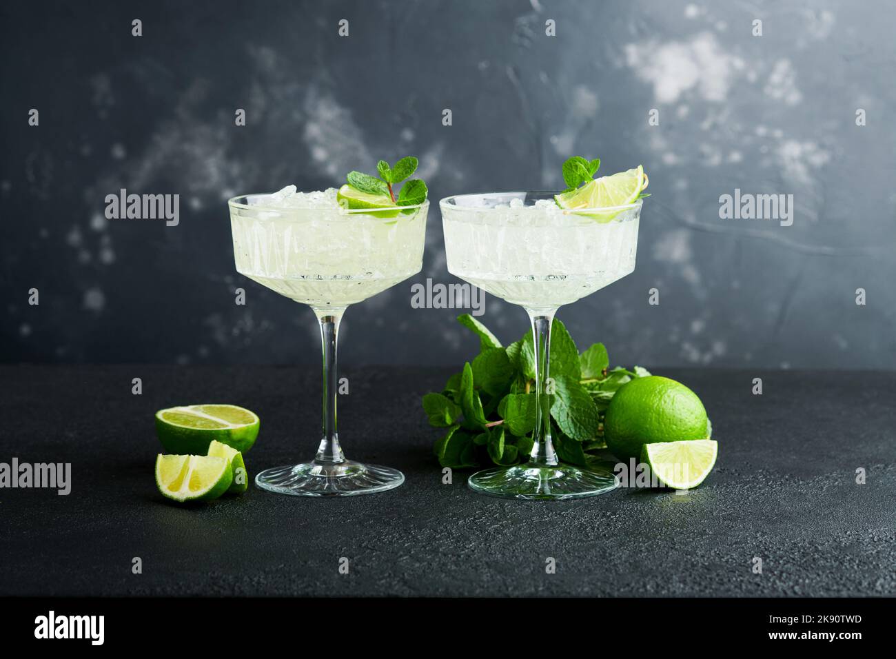 Cocktail de Margarita avec citron vert, tequila, menthe et glace sur table sombre avec rétroéclairage incroyable, espace de copie. Margarita classique ou cocktail Daiquiry. Carte à barres Banque D'Images